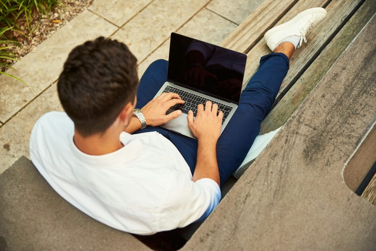 "Seorang anak muda bekerja dengan laptop di ruang terbuka, melambangkan pentingnya soft skill seperti komunikasi, manajemen waktu, dan kreativitas dalam mencapai kesuksesan di era digital.